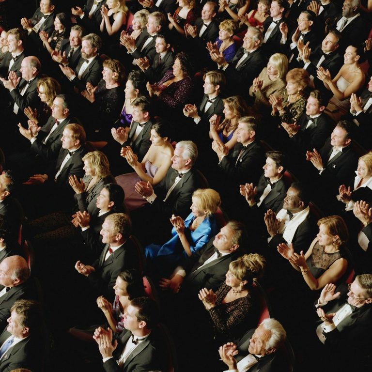 Eine Menge von elegantly gekleideten Menschen, die applaudieren in einem festlichen Veranstaltungsort.